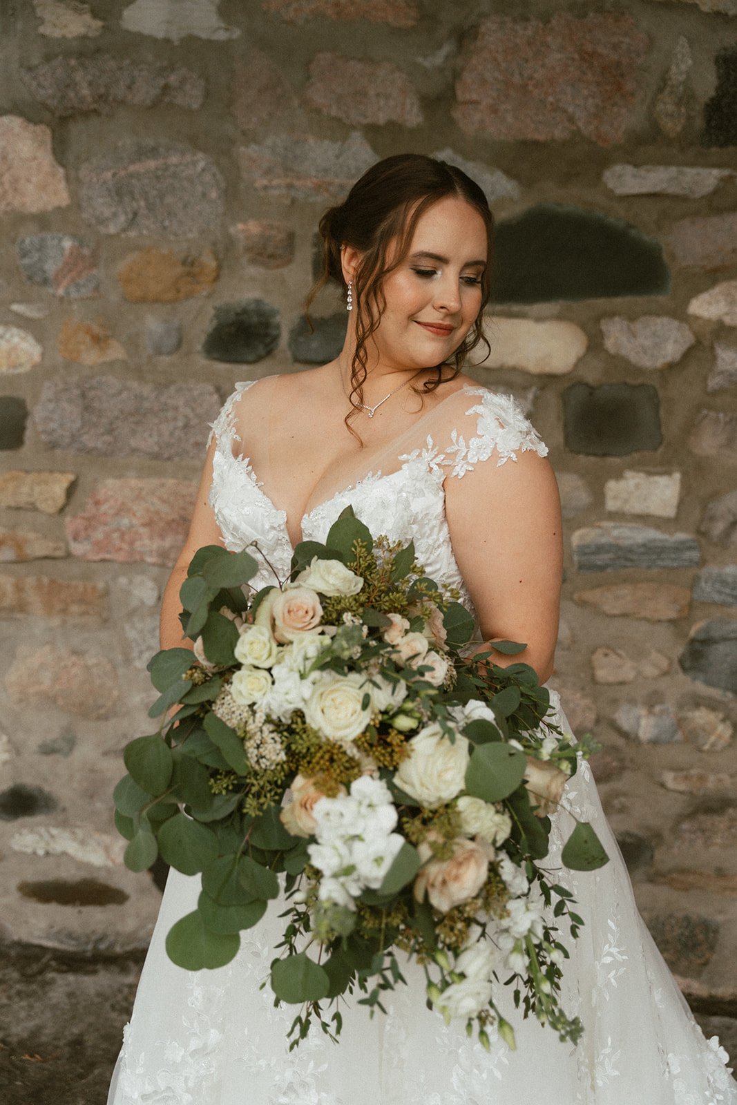 Bride with cascading bouquet of white roses and eucalyptus